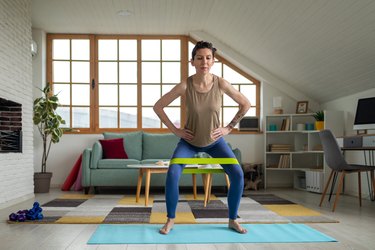 Adult performing monster walk in living room on blue yoga mat