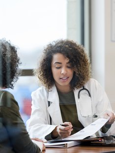 woman doctor in white coat reviews a patient's medical records in glass conference room