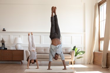 Father and daughter practice handstands together in the living room