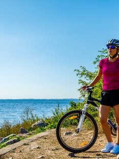 Woman cycling for exercise on trail near ocean