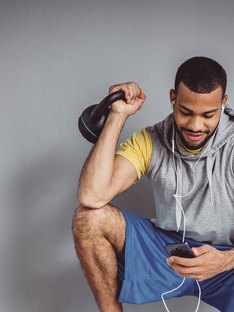 Man listening to workout music holding a kettlebell
