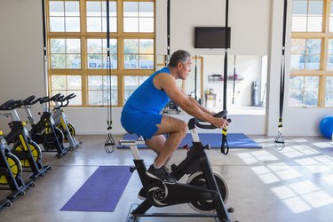 Person wearing blue tank top and shorts riding an exercise bike indoors