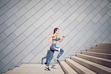 Girl is runing on the city stairs and listening the music